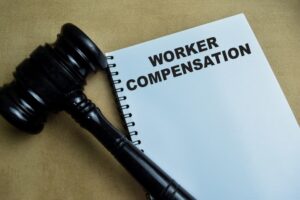 The concept of Worker Compensation written on a notebook placed on a wooden table, symbolizing legal rights and employee benefits.