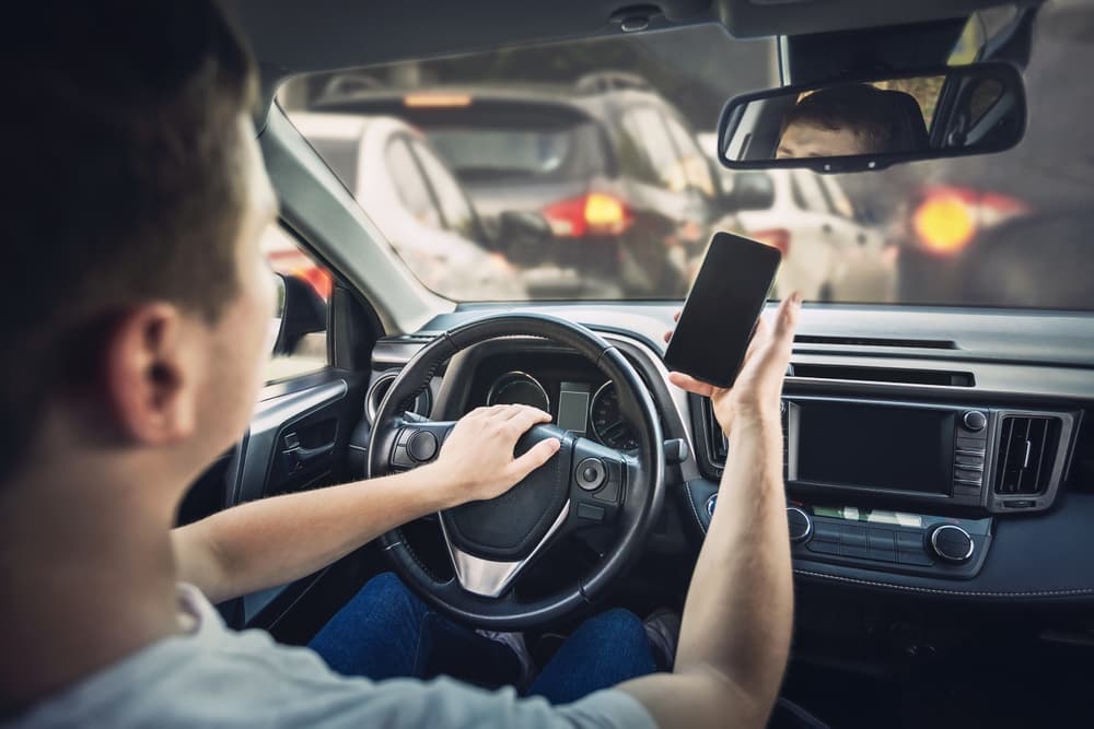 An angry driver honks the car horn in frustration over a traffic jam ahead. He drives aggressively while using his phone, violating traffic laws.