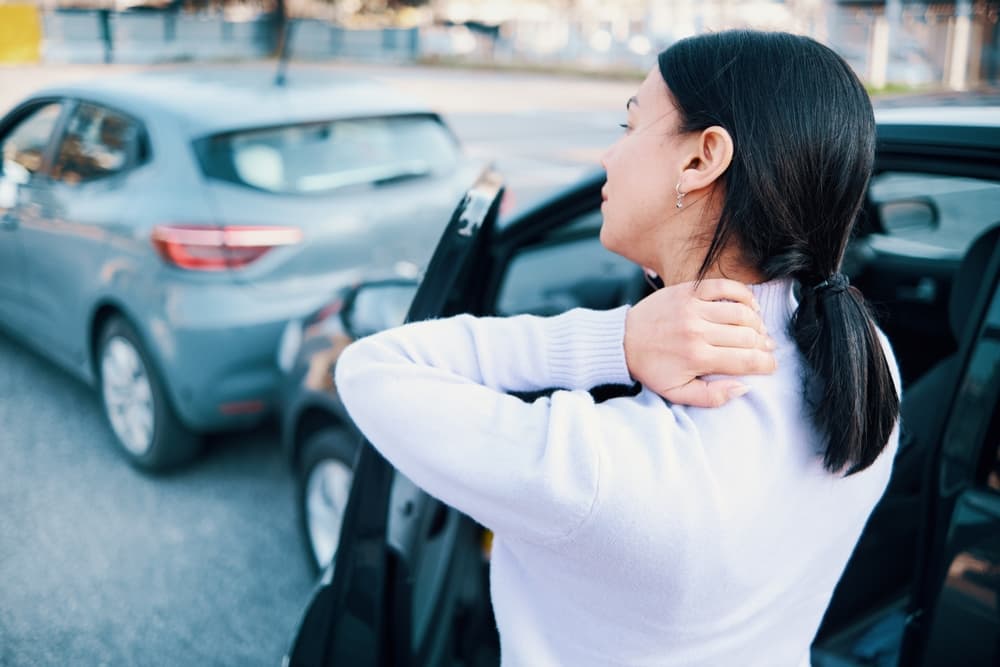 A woman experiencing neck pain after a car accident pile-up, suffering from whiplash due to the collision.