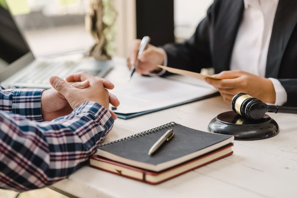 A justice lawyer meeting with contract papers and a judge’s gavel on the table in a courtroom. The attorney is actively working, symbolizing justice, law, and the court judge's role.