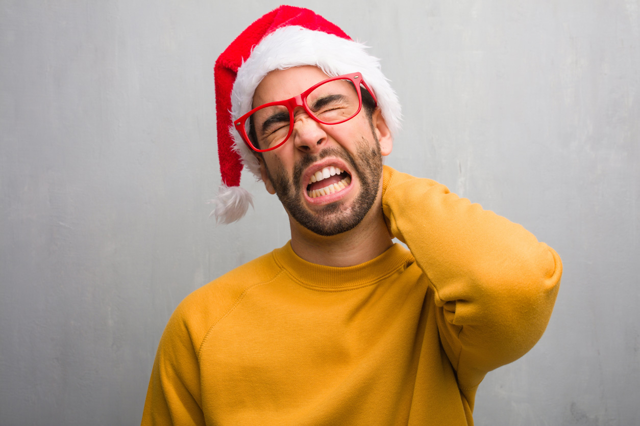 man holding neck in pain with santa hat