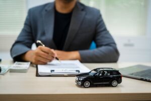 A close-up of a customer signing a car insurance contract at an agency. 